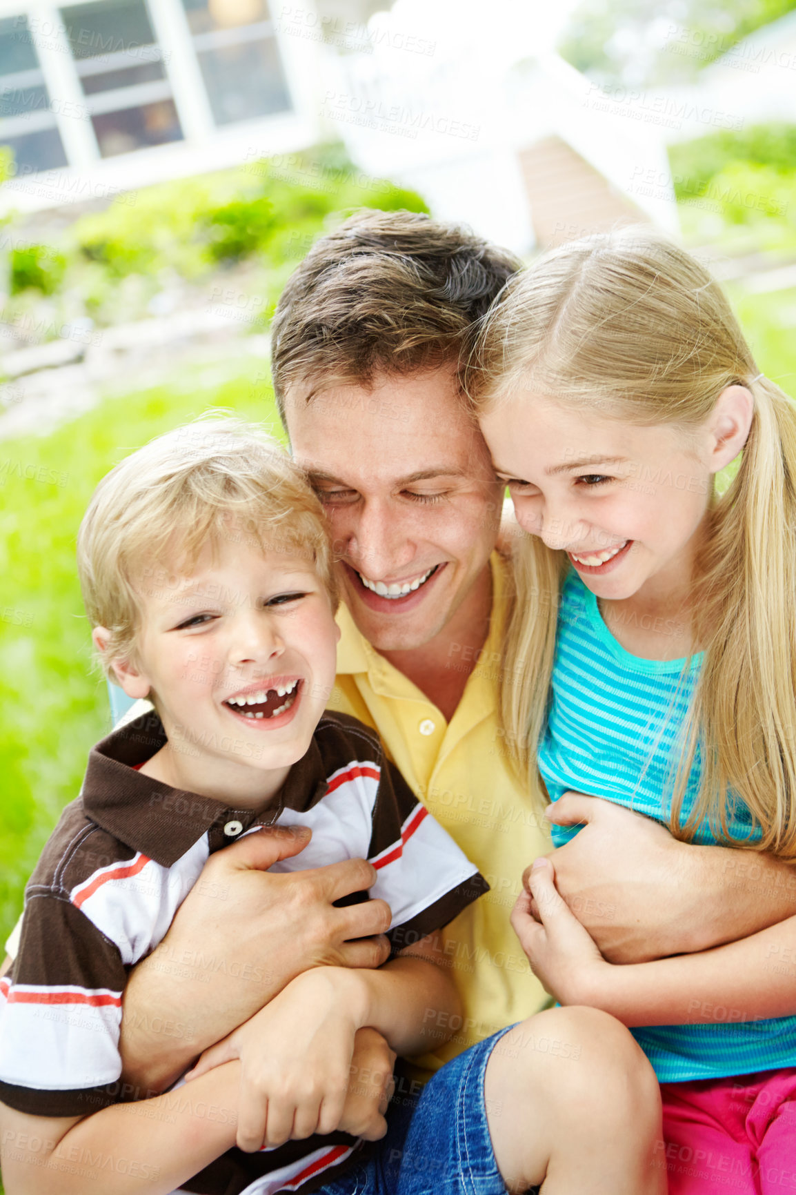 Buy stock photo Handsome young father holding his two children with a happy smile