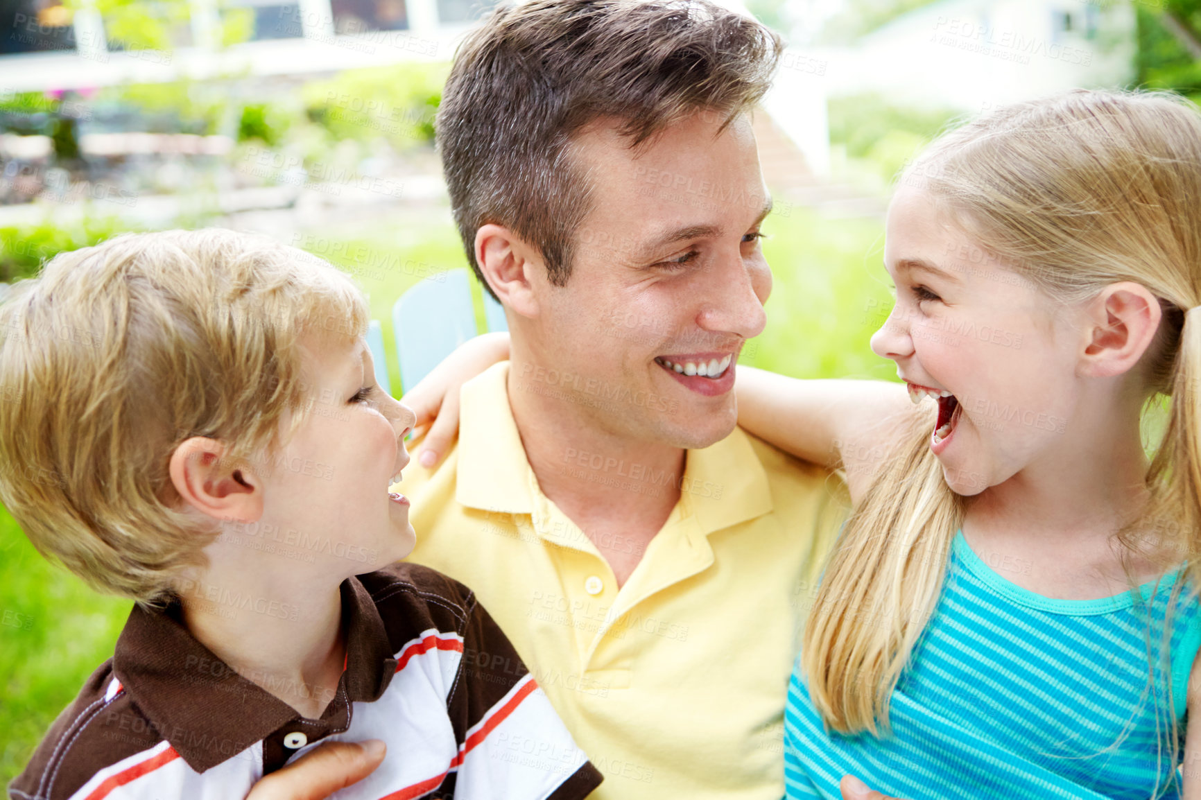 Buy stock photo Handsome young father holding his two children with a happy smile