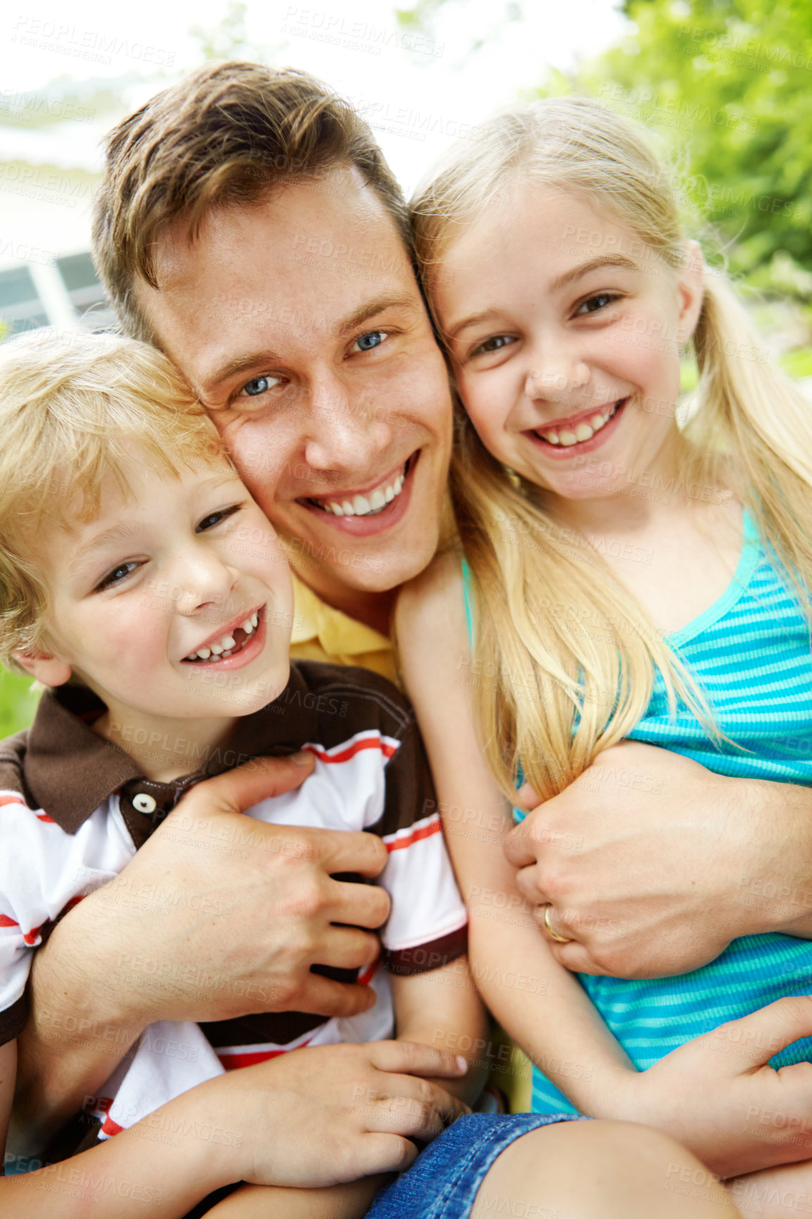 Buy stock photo Handsome young father holding his two children with a happy smile