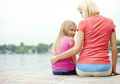 Buy stock photo A back image of a mother and daughter sitting by a river