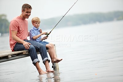 Buy stock photo A father teaching his son how to fish whilst sitting on a ledge over a river