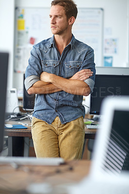 Buy stock photo A young casual businessman leaning against his desk in his office