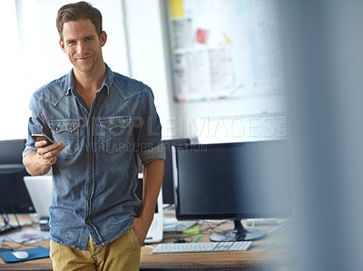 Buy stock photo A young man reading his text messages while standing in his office