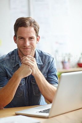 Buy stock photo A young man sitting at his desk while smiling at the camera