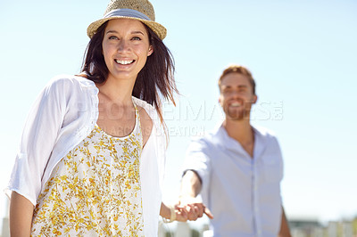 Buy stock photo Young couple holding hands with smile for summer vacation, travel or journey together in the outdoors. Portrait of beautiful woman leading her boyfriend by the hand on a sunny day for the holiday