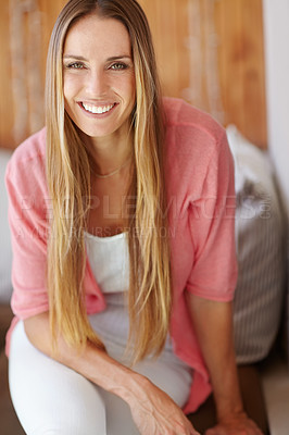 Buy stock photo A beautiful young woman smiling at the camera as she sits on her sofa at home