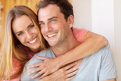 Buy stock photo A beautiful young woman embracing her husband from behind as they sit on the couch