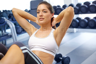 Buy stock photo A beautiful young woman doing sit-ups at the gym