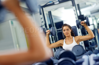 Buy stock photo A beautiful young woman exercising with weights at the gym