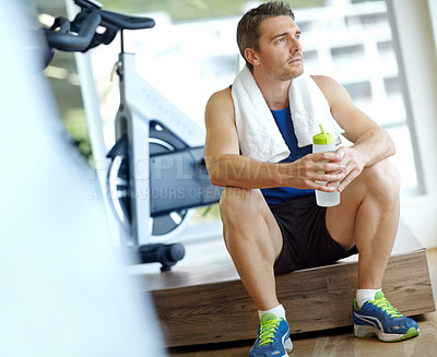 Buy stock photo A handsome man sitting at the gym taking a break and having a drink of water