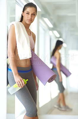 Buy stock photo A gorgeous young woman standing at the gym holding an exercise mat and a bottle of water