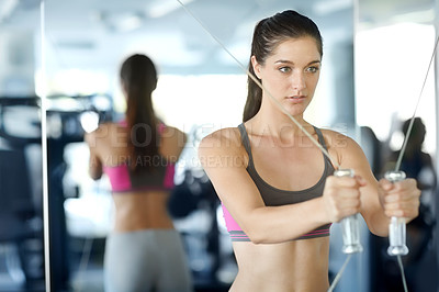 Buy stock photo A beautiful young woman doing weight-training at the gym