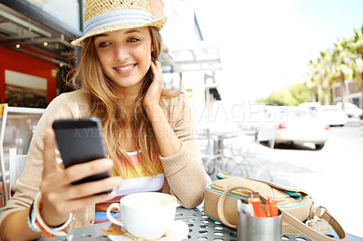 Buy stock photo A casual young woman sending a text message while sitting at a sidewalk cafe in the city - copyspace