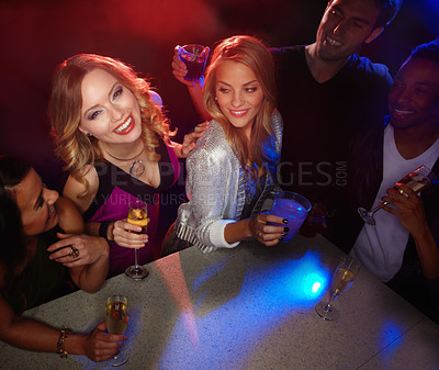 Buy stock photo A group of friends smiling at the camera while they enjoy drinks in a nightclub