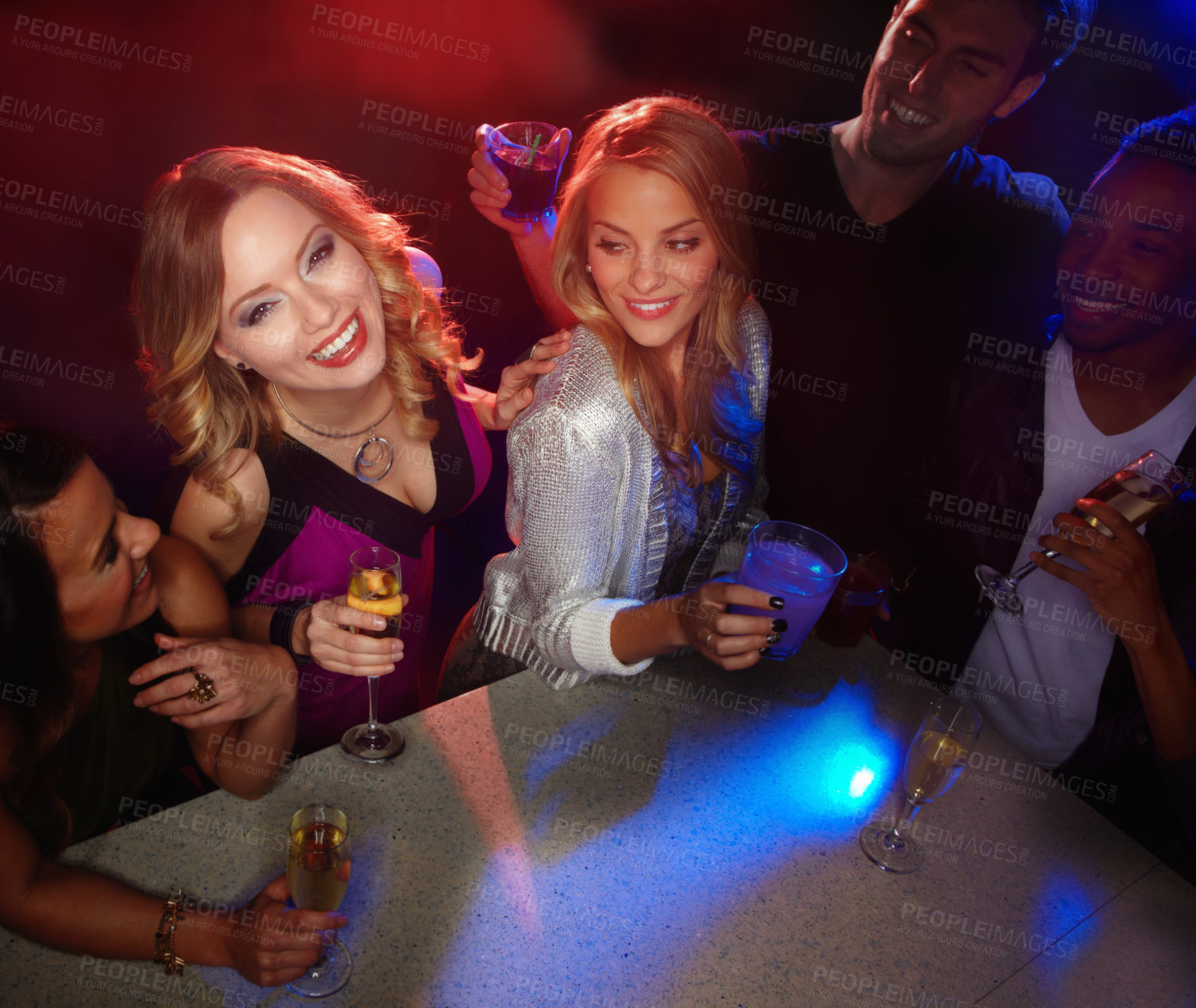 Buy stock photo A group of friends smiling at the camera while they enjoy drinks in a nightclub