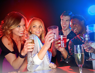 Buy stock photo A multi-ethnic group of friends toasting with their drinks in a nightclub