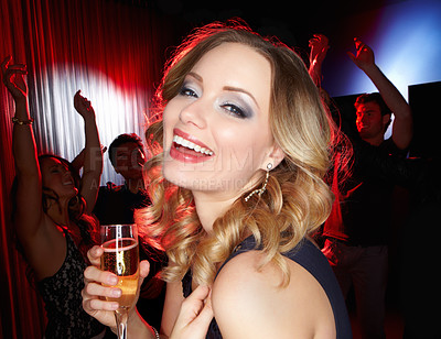 Buy stock photo A lovely young blonde woman smiling at the camera while standing on the dancefloor holding a glass of wine