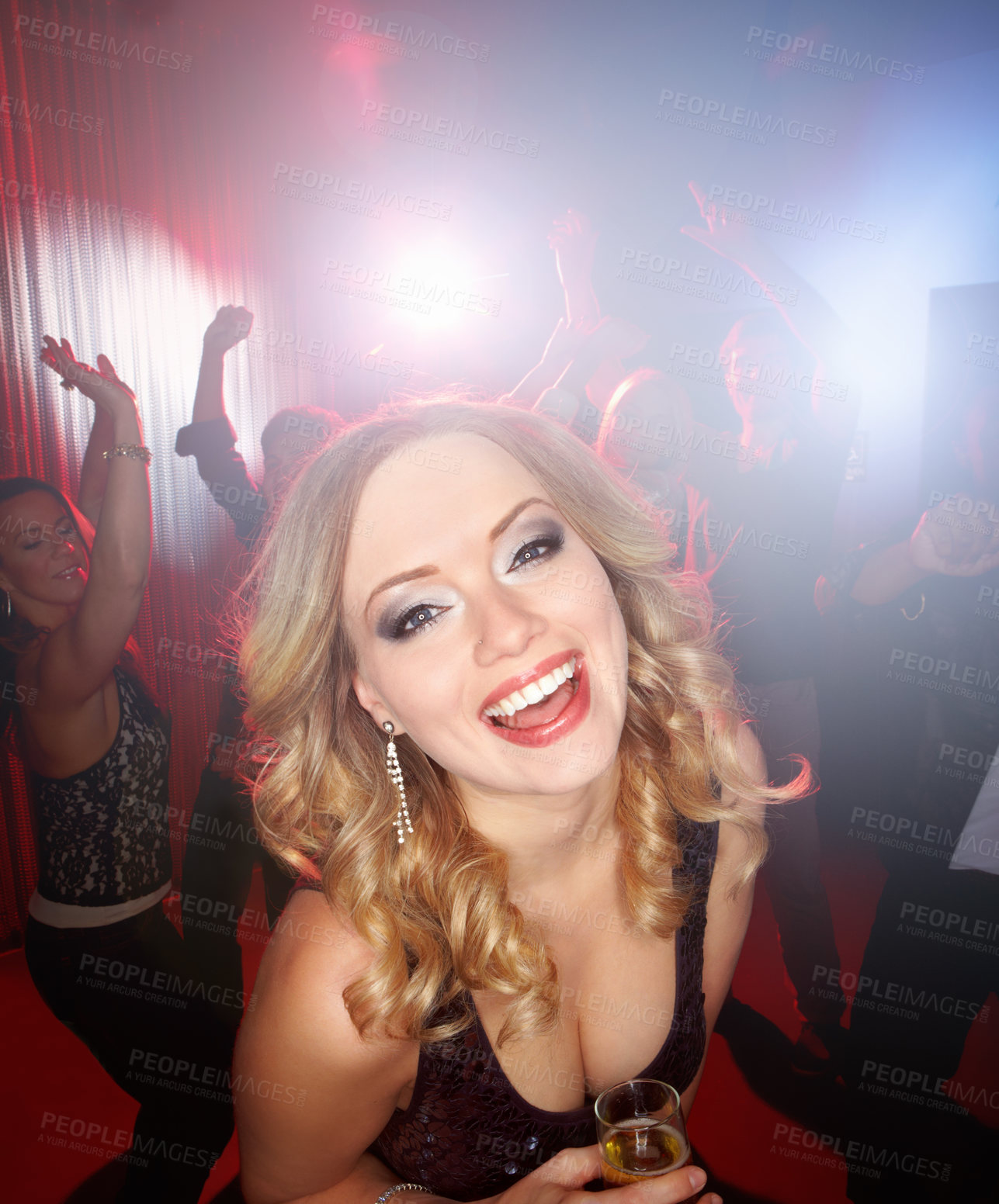 Buy stock photo A lovely young blonde woman smiling at the camera while standing on the dancefloor holding a glass of wine