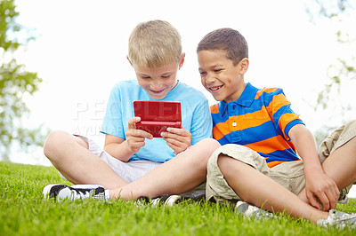 Buy stock photo Two fascinated little boys holding a nintendo gaming console and playing on it