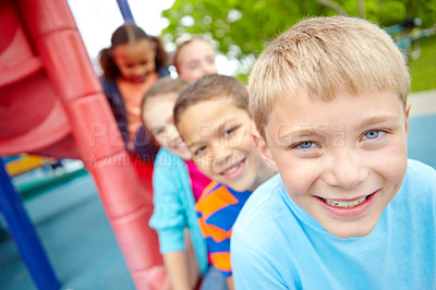 Buy stock photo A happy group of multi-ethnic children sitting happily on a slide in a play park