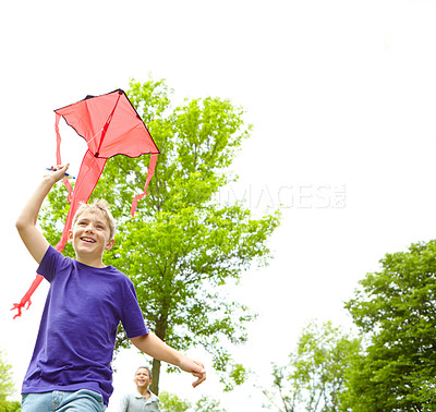 Buy stock photo A happy young boy flying a kite outside in a park
