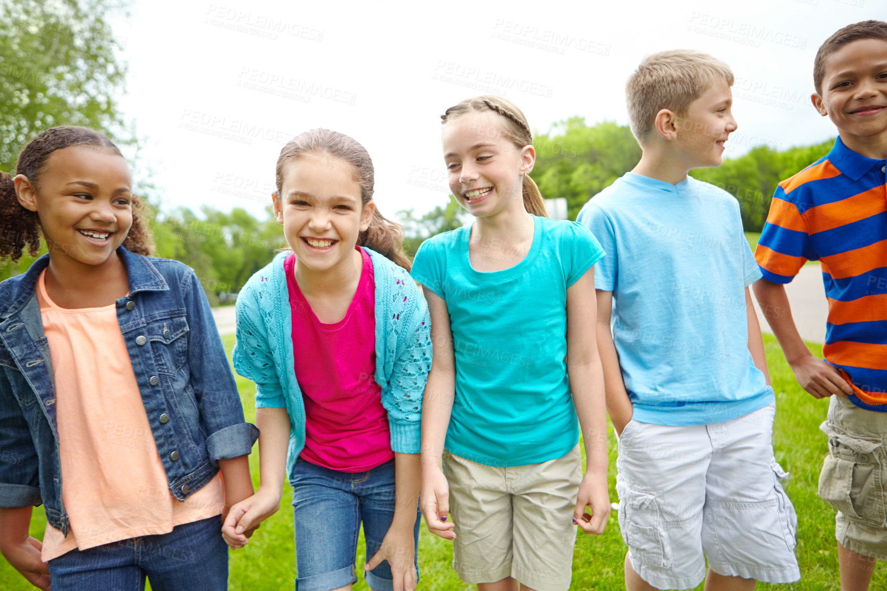 Buy stock photo A multi-ethnic group of kids standing outside in a park