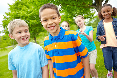 Buy stock photo Two young boys standing outside smiling at the camera with their friends behind them