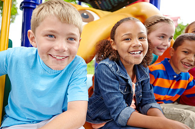 Buy stock photo A happy group of multi-ethnic children sitting happily on a slide in a play park