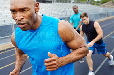 Buy stock photo Close up of a male athlete with his competitors in the background starting the race