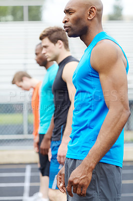 Buy stock photo Side view of a male runner in a line up of other athletes at the start of the track
