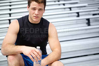 Buy stock photo Cropped close up portrait of a male runner sitting on the rafters holding a water bottle