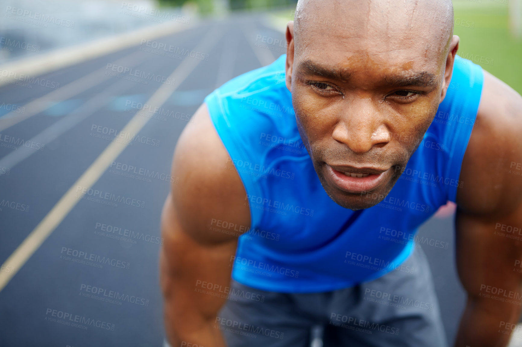 Buy stock photo Cropped close up of a male athlete looking away from the camera at the start of the track