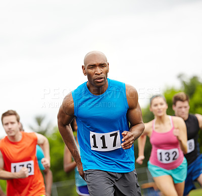 Buy stock photo Front view of a male runner in first place with other competitors close behind
