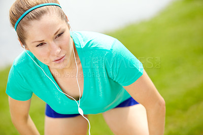 Buy stock photo Cropped front view of a female jogger leaning forward and listening to music