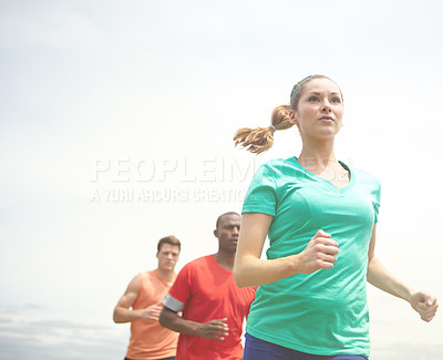 Buy stock photo Shot of female runner looking ahead with other athletes in the background
