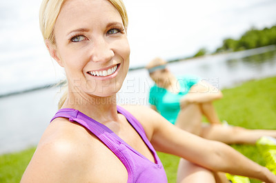 Buy stock photo Close up of a female athlete looking over her shoulder while stretching her leg muscles