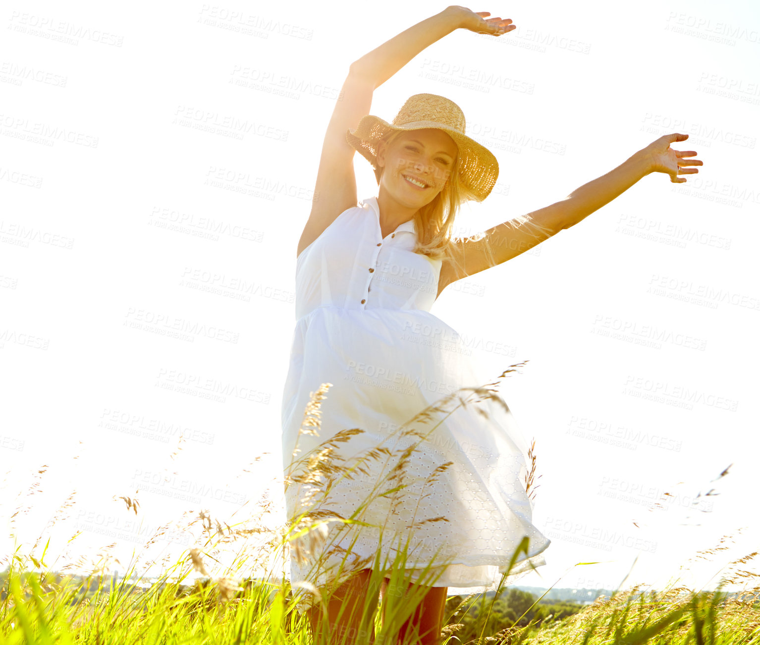 Buy stock photo A carefree young woman standing with her arms outstretched in a meadow while smiling blissfully