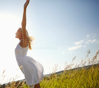 Buy stock photo A young woman in a field with her arms outstretched