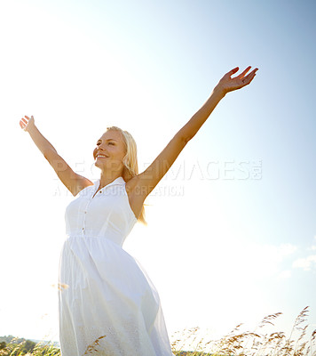 Buy stock photo A young woman in a field with her arms outstretched