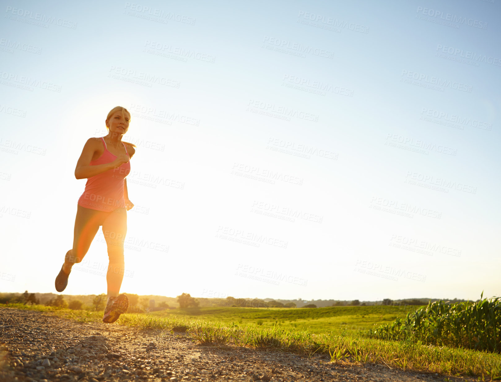 Buy stock photo A young woman running along a dirt road