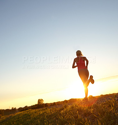 Buy stock photo A beautiful young woman jogging as the sun sets in front of her