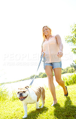 Buy stock photo Happy, walking and woman with dog in nature for exercise, training and adventure outdoors on weekend. Pets, animal care and owner with Bulldog in park for wellness, health and fitness on field