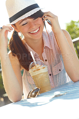 Buy stock photo An adolescent girl laughing as she speaks on her cellphone while sitting at an outdoor cafe