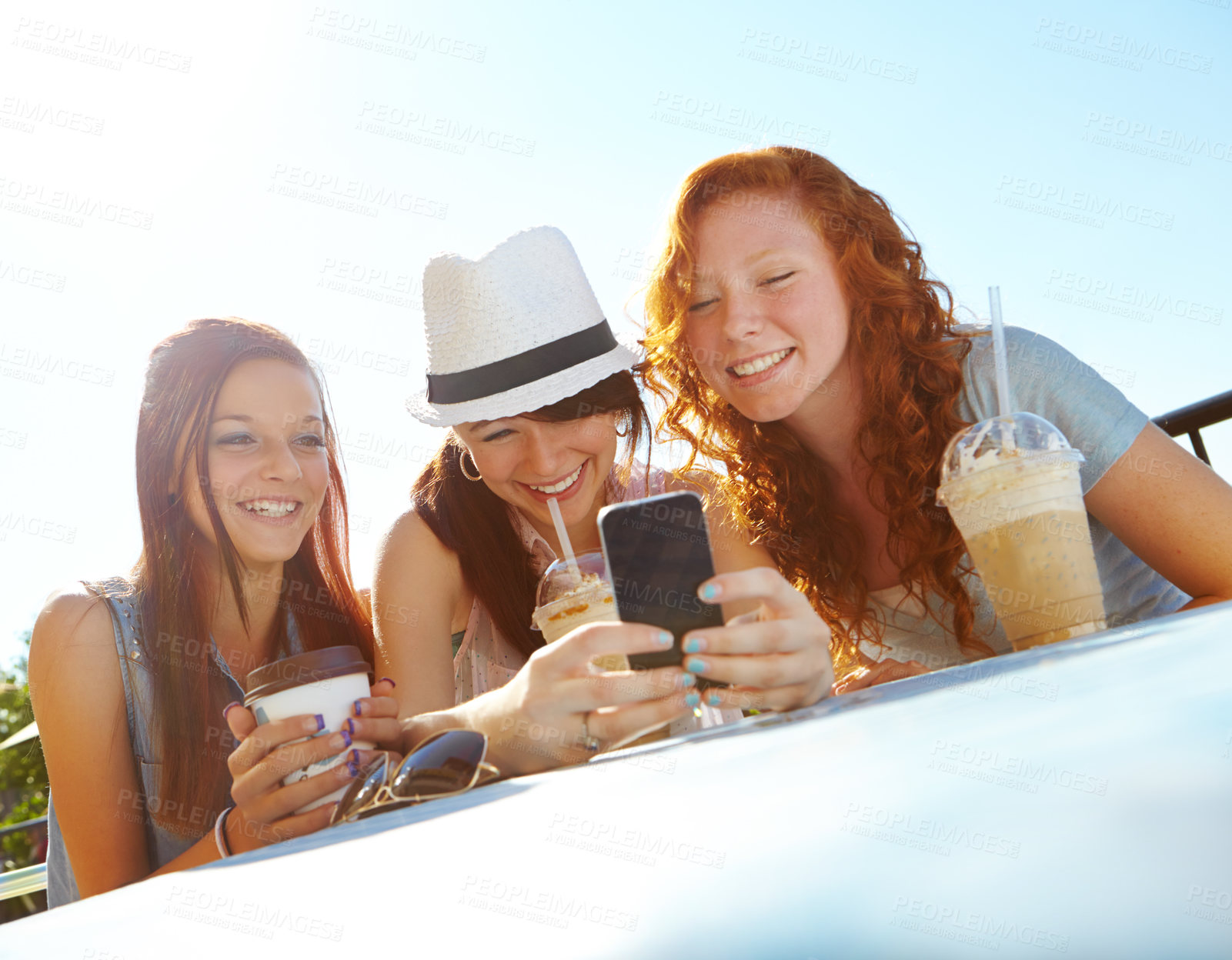 Buy stock photo Three adolescent girls sitting at an outdoor cafe texting on a cellphone