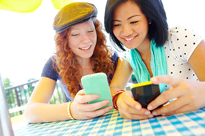 Buy stock photo Two teenage girls sitting outside texting on their cellphones