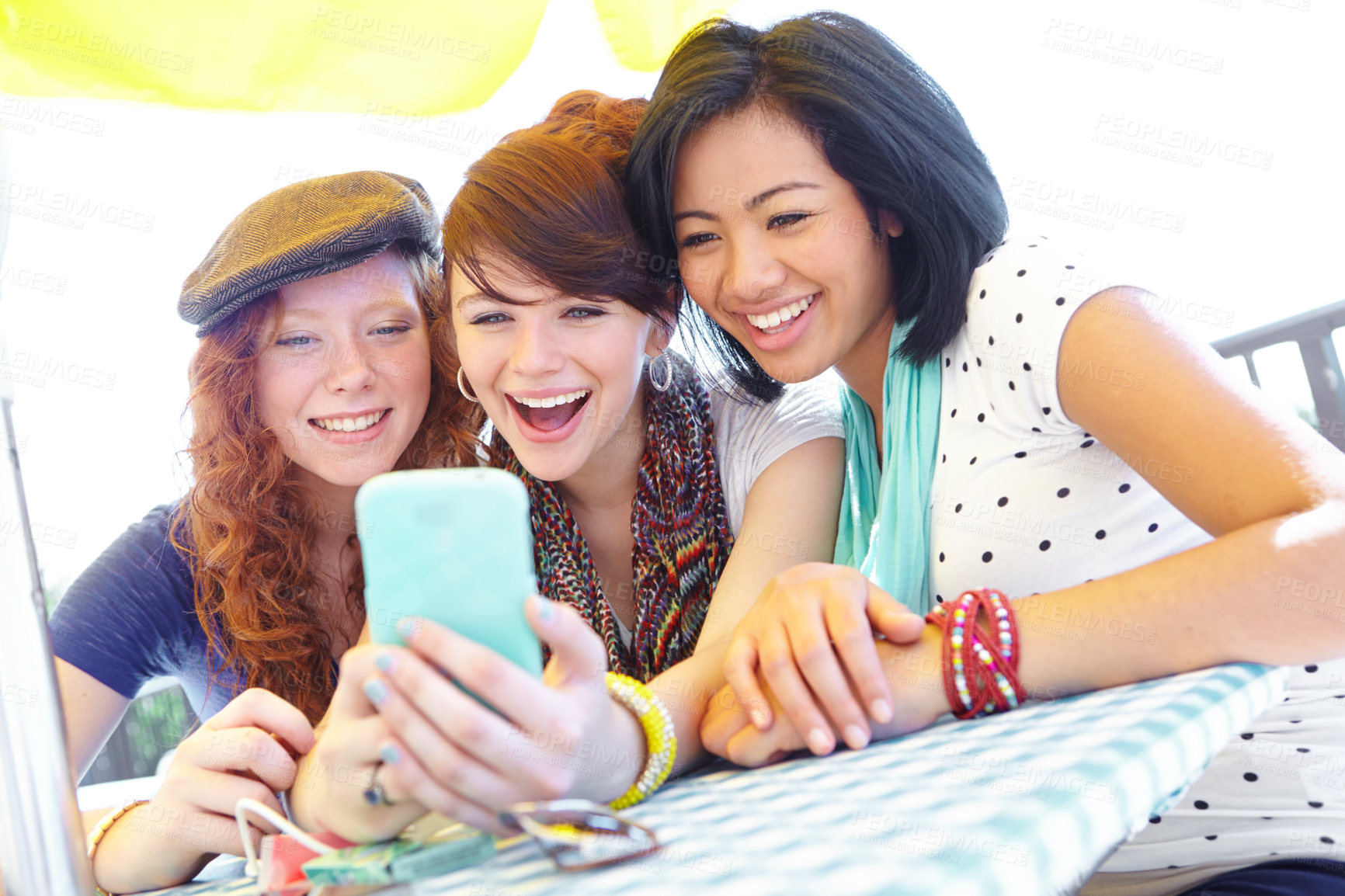 Buy stock photo A group of adolescent girls laughing as they look at something on a smartphone screen