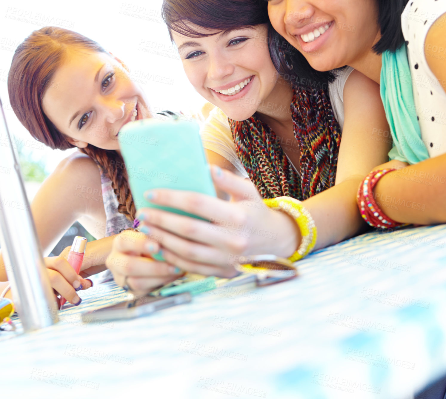 Buy stock photo A group of adolescent girls laughing as they look at something on a smartphone screen