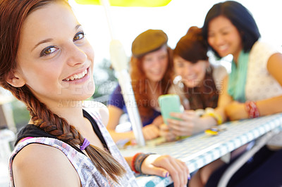 Buy stock photo An adolescent girl smiling at the camera with her friends sitting in the background