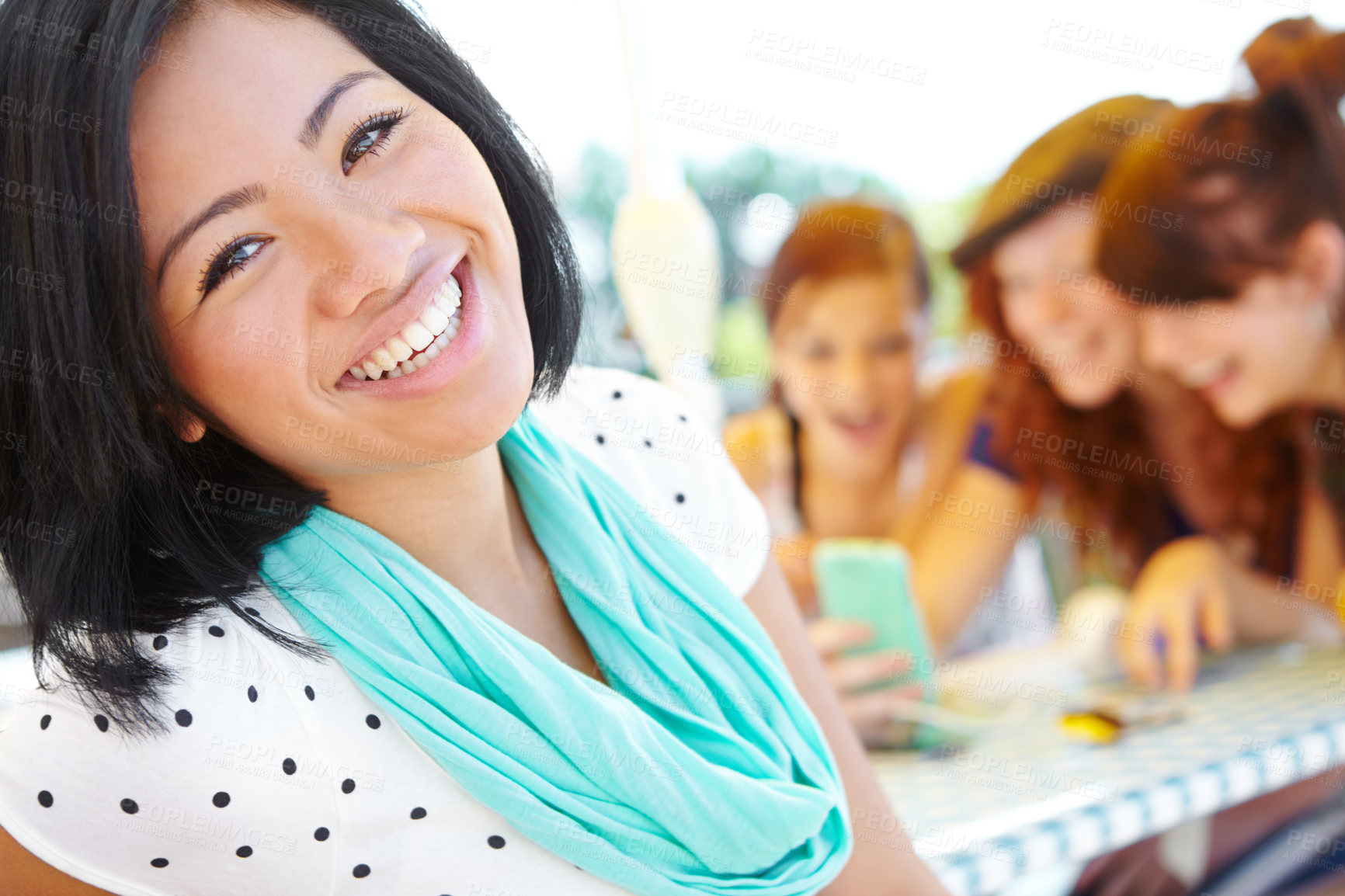 Buy stock photo An ethnic adolescent girl smiling at the camera with her friends sitting in the background