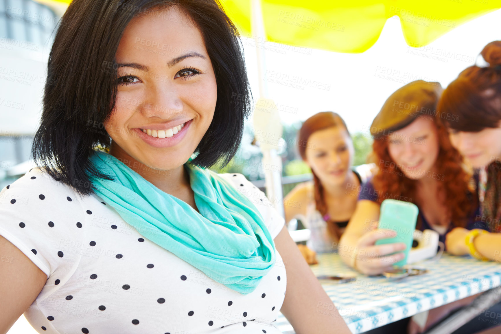 Buy stock photo An ethnic adolescent girl smiling at the camera with her friends sitting in the background